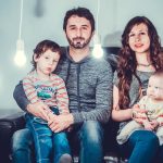 A loving family portrait with parents and children sitting together in a modern, well-lit room.
